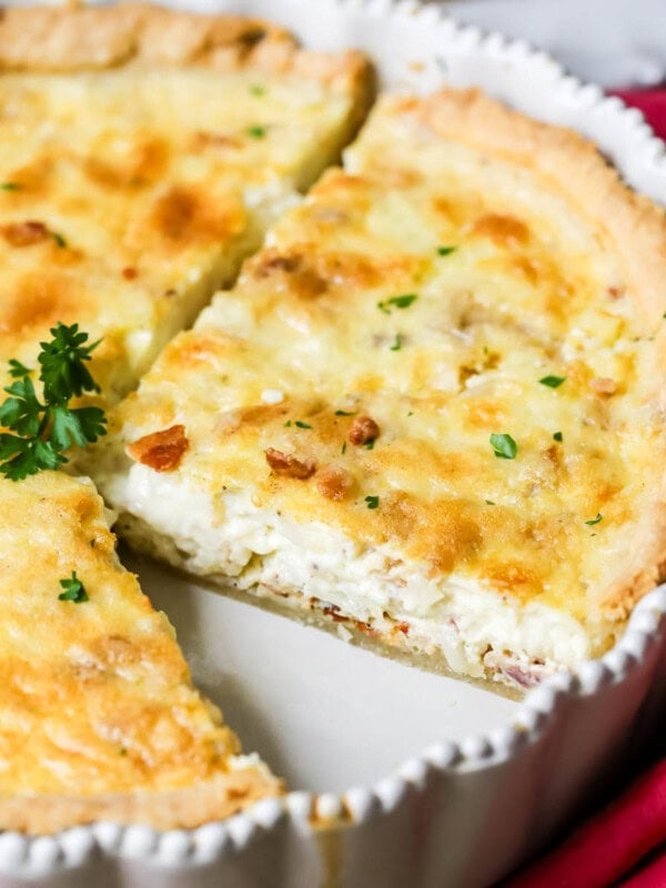 Quiche lorraine in a pan with several slices cut into it.