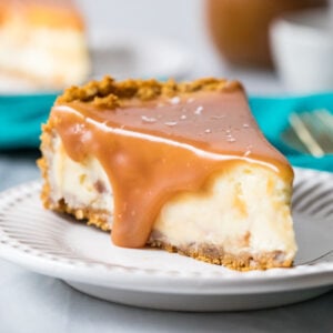 Slice of salted caramel cheesecake topped with caramel sauce and sea salt on a plate.