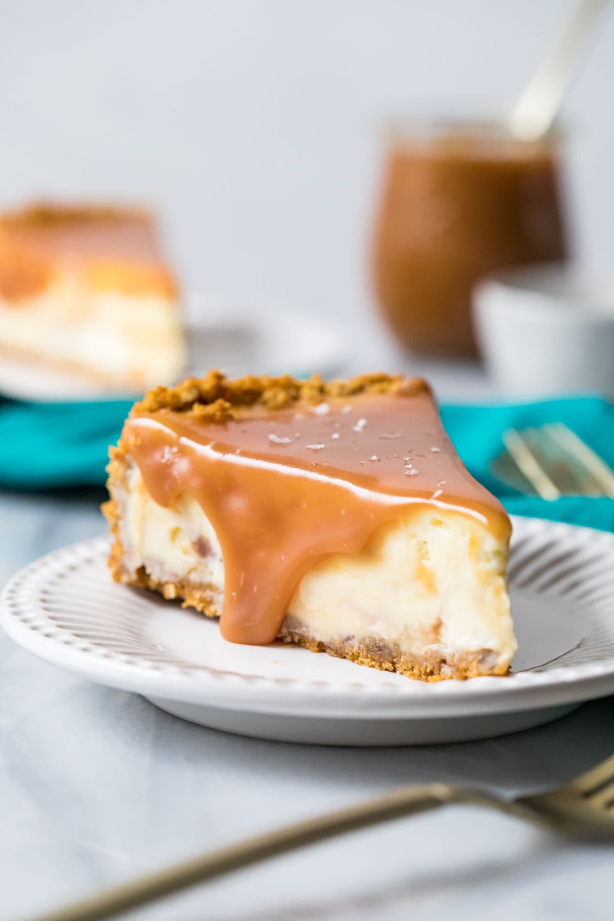Slice of salted caramel cheesecake topped with caramel sauce and sea salt on a plate.
