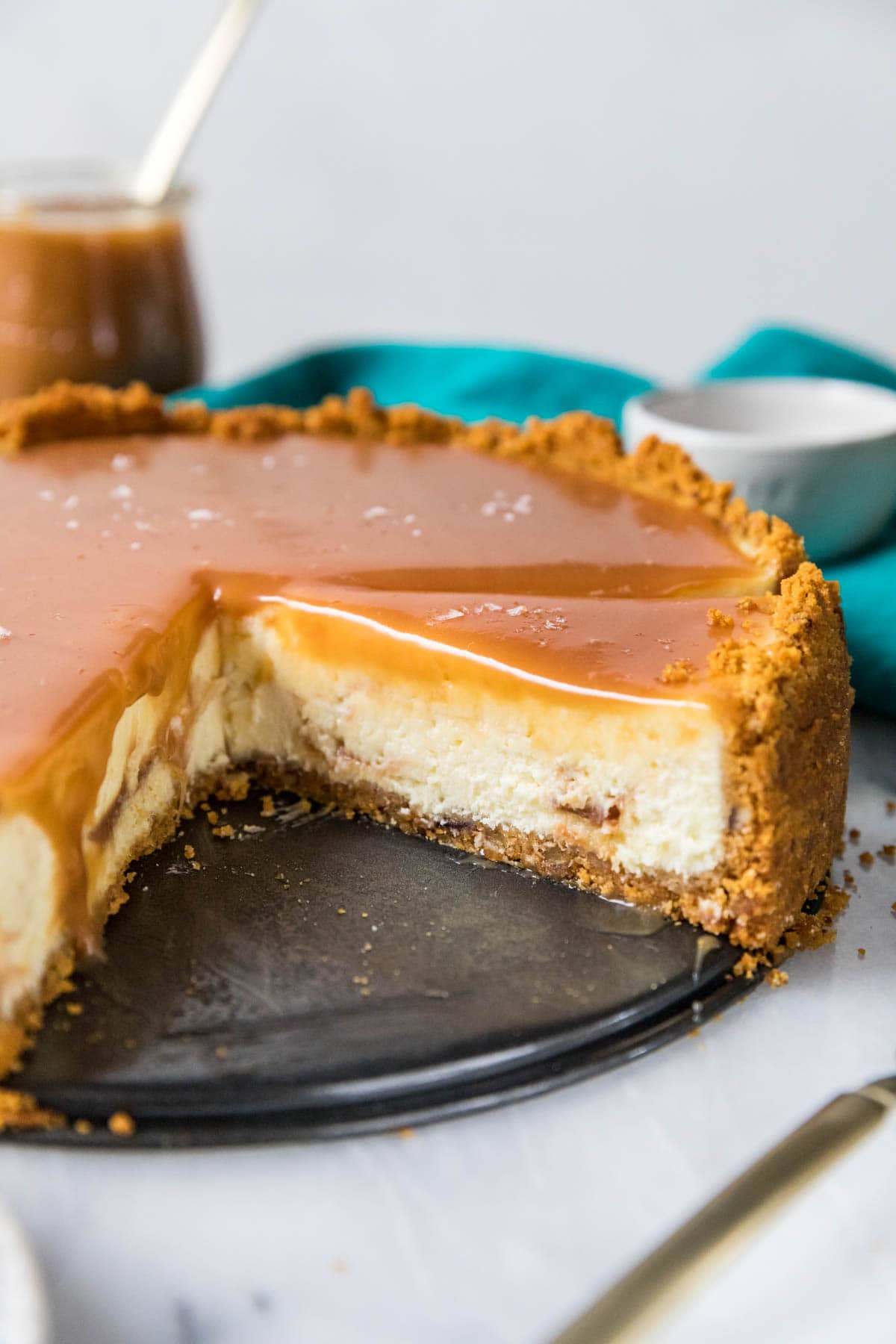 Caramel topped salted caramel cheesecake that's missing several slices.