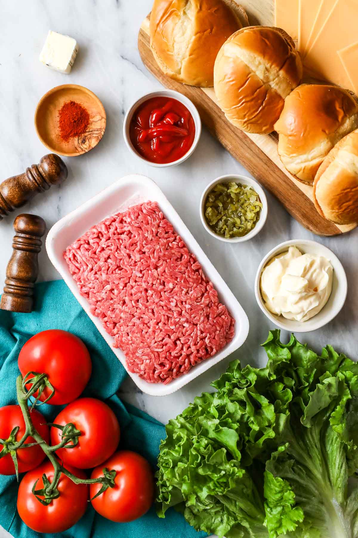 Overhead view of ingredients including ground beef, seasonings, lettuce, tomato, and more.