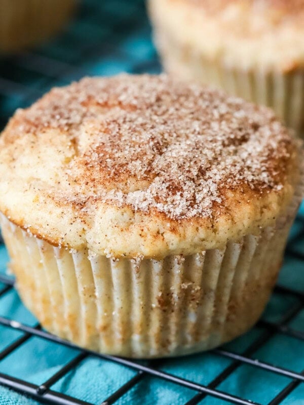 Cinnamon muffins on a cooling rack with a teal towel underneath.