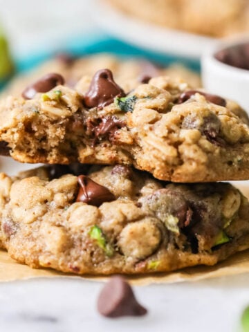 Two zucchini cookies stacked on top of each other with the top cookie missing a bite.