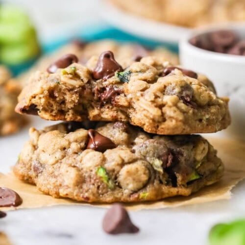 Two zucchini cookies stacked on top of each other with the top cookie missing a bite.