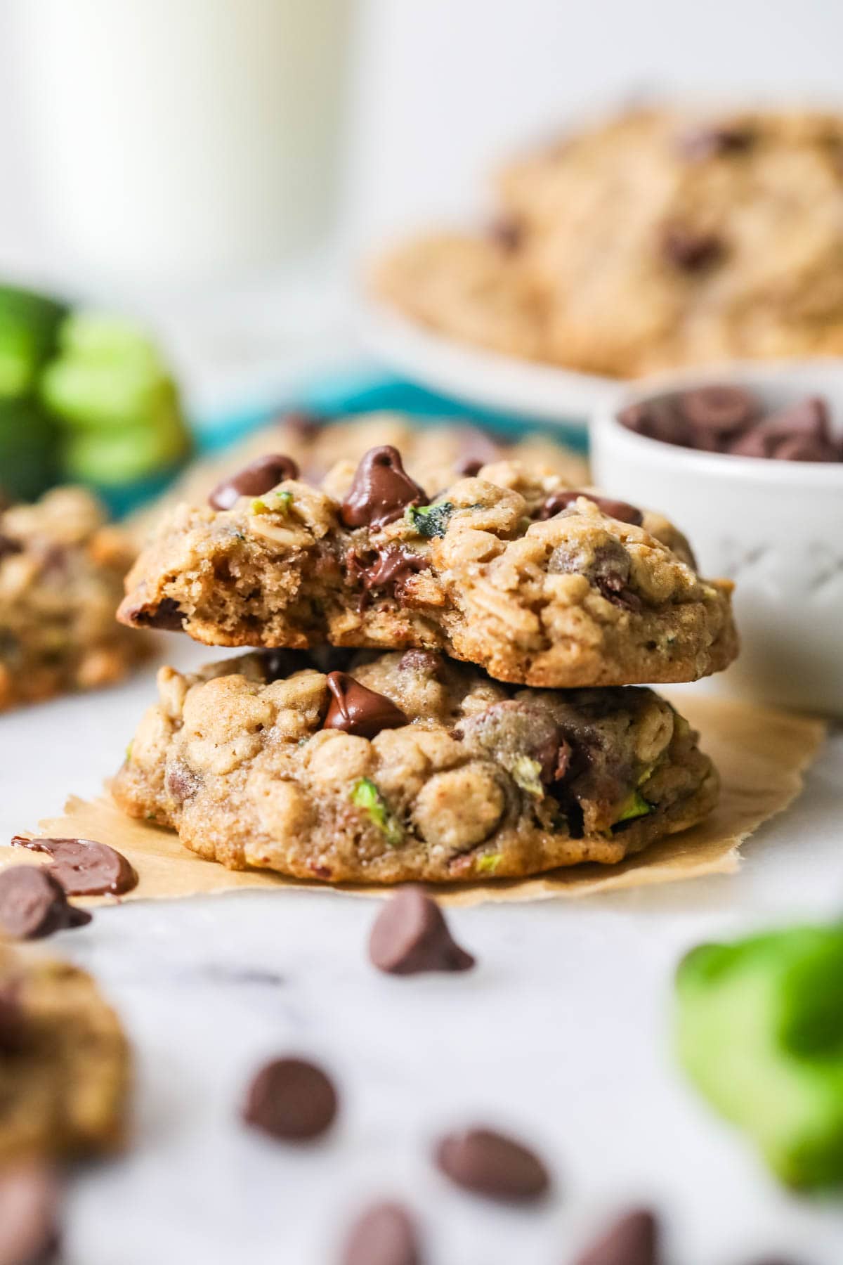 Two zucchini cookies stacked on top of each other with the top cookie missing a bite.