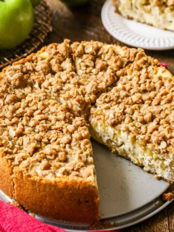 Whole apple pie cheesecake that's been cut into slices with one slice missing.