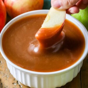Dipping an apple slice into a white dish full of caramel dip