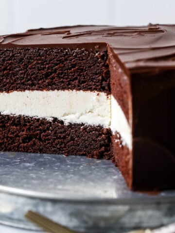 Cross section of a ding dong cake made with a creamy white filling and chocolate ganache topping.