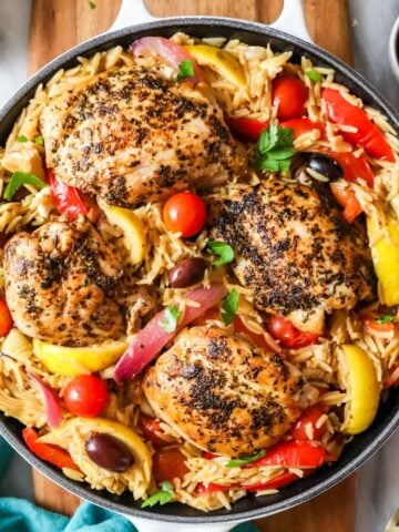 Overhead view of Greek chicken orzo in a cast iron skillet.