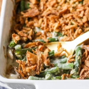Serving spoon scooping green bean casserole out of a dish.