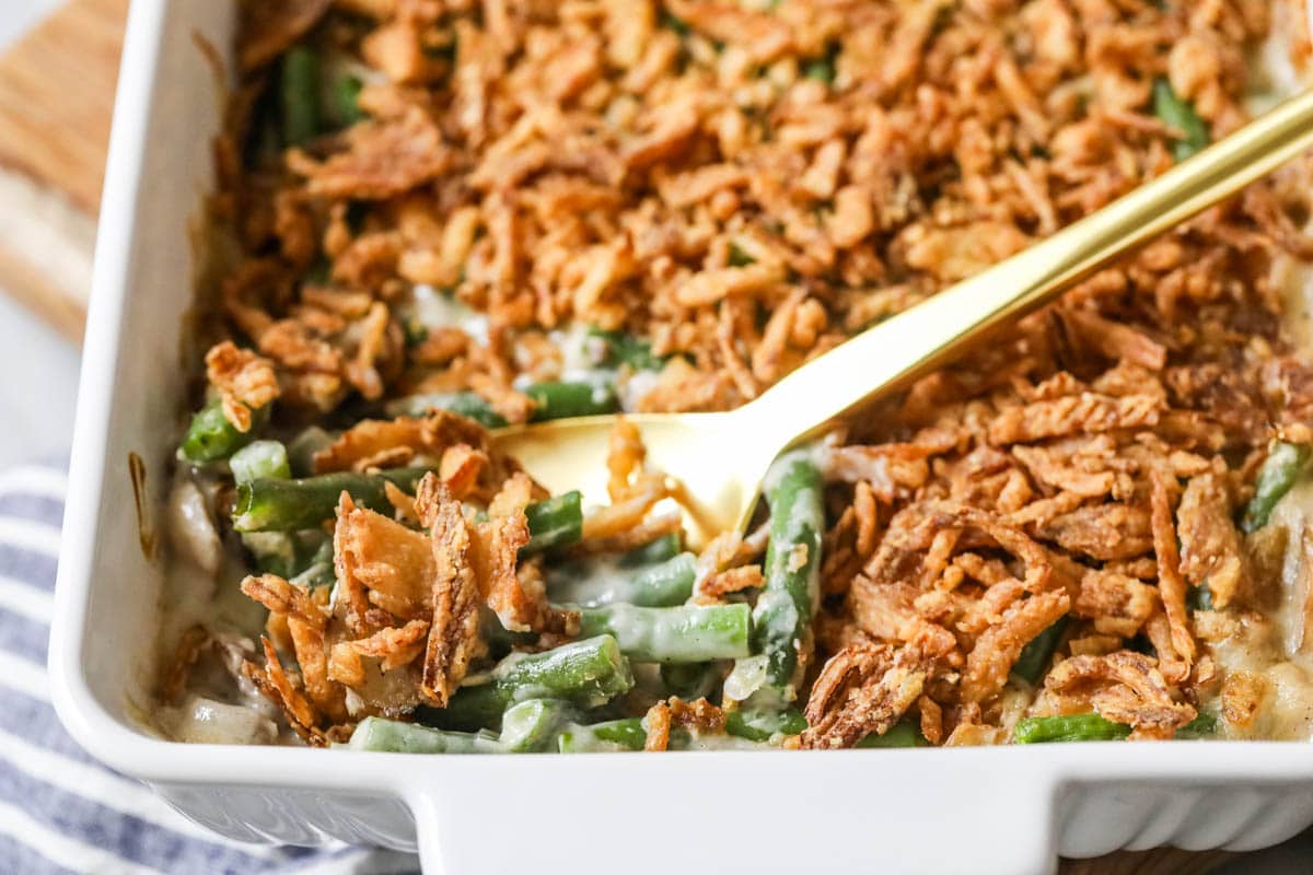 Serving spoon scooping green bean casserole out of a dish.
