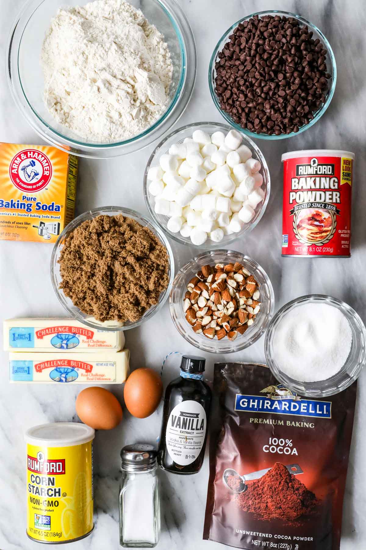 Overhead view of ingredients including brown sugar, cocoa powder, mini marshmallows, almonds, and more.
