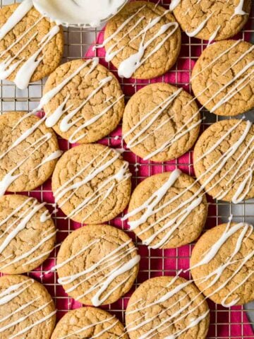 Overhead view of spice cookies topped with a vanilla glaze drizzle on a cooling rack.