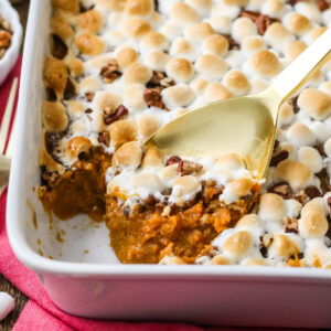 Gold spoon scooping sweet potato casserole out of a white dish.