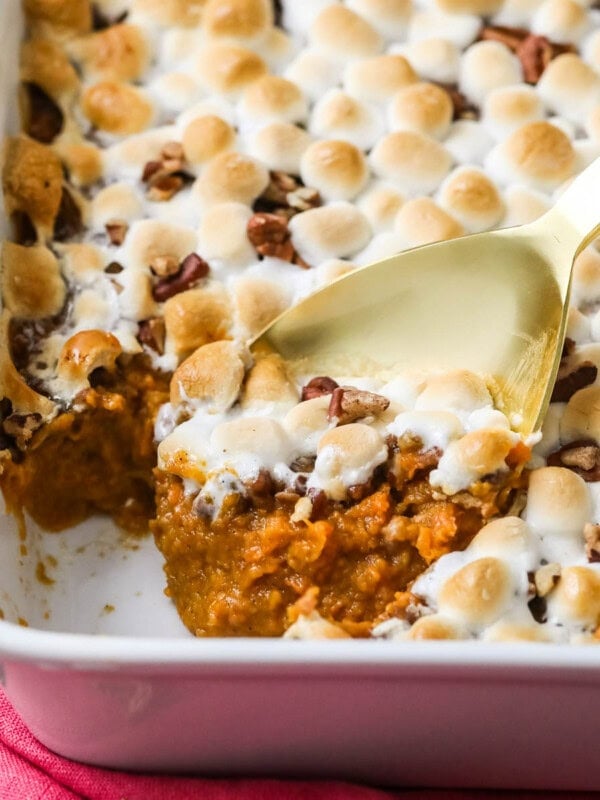 Gold spoon scooping sweet potato casserole out of a white dish.