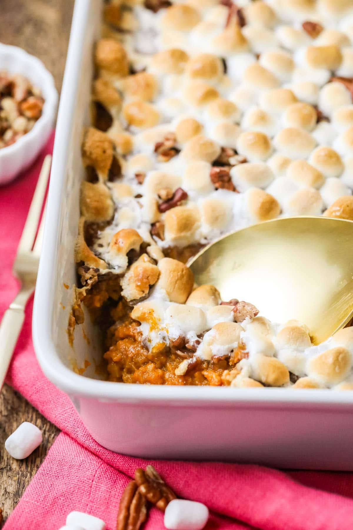 Gold spoon scooping sweet potato casserole out of a white dish.