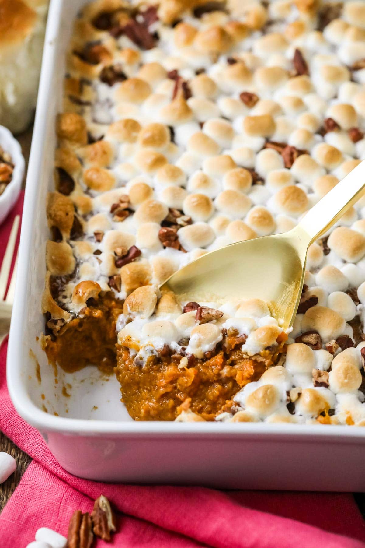 Gold spoon scooping sweet potato casserole out of a white dish.