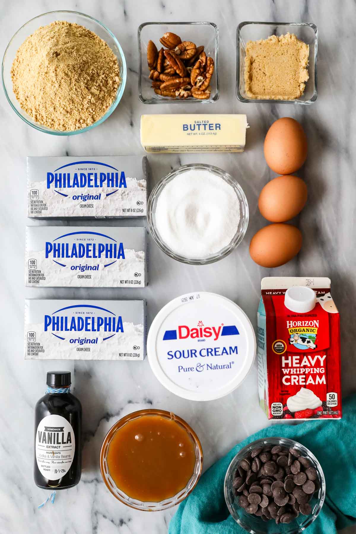 Overhead view of ingredients including cream cheese, pecans, caramel sauce, and more.
