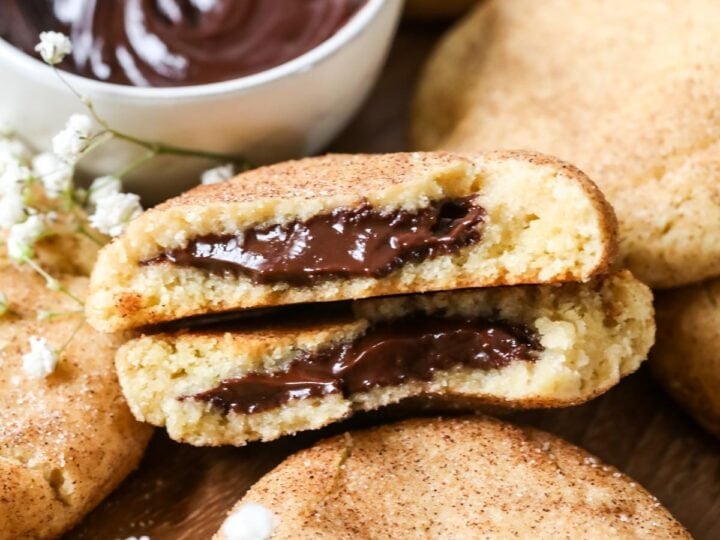 Two halves of a chocolate filled churro cookie among other cookies.