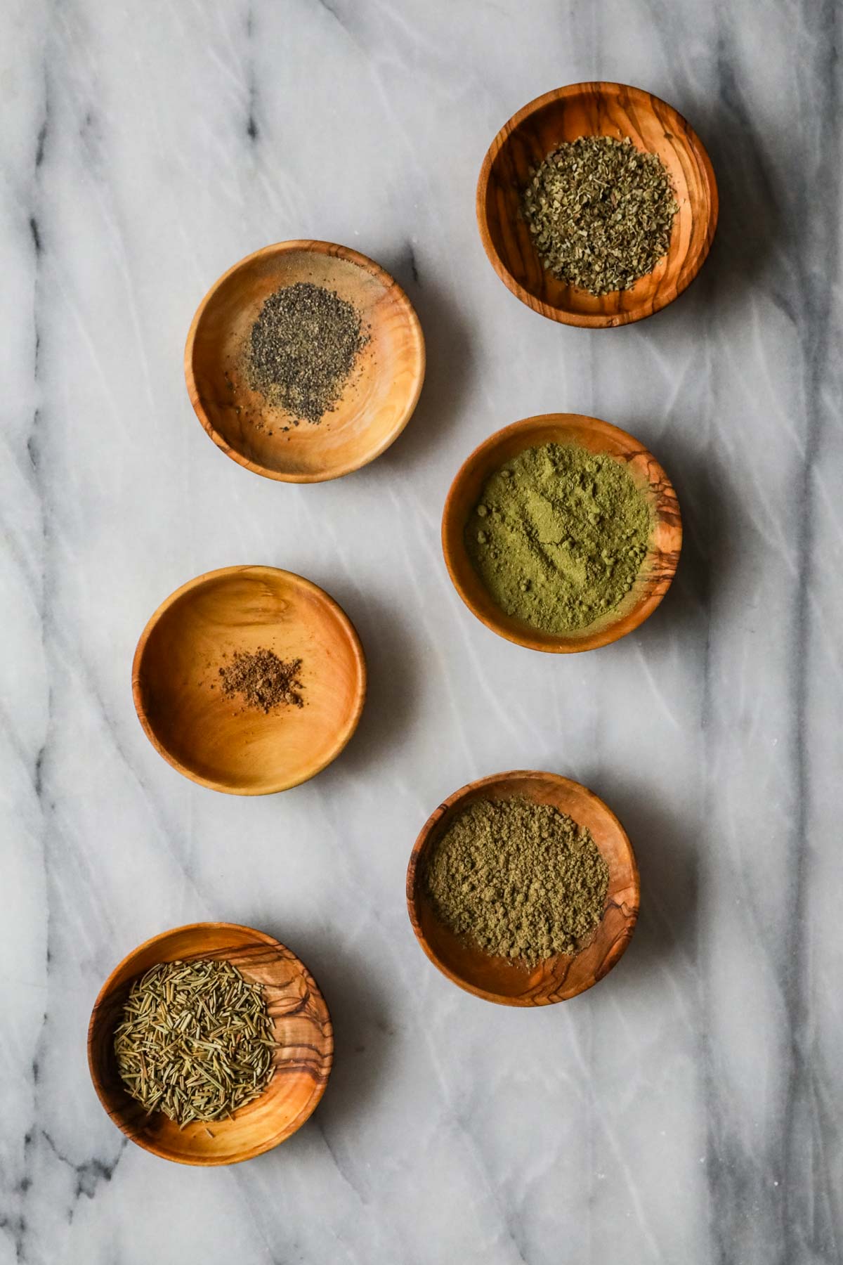 Overhead view of six spices in small, individual wood dishes.