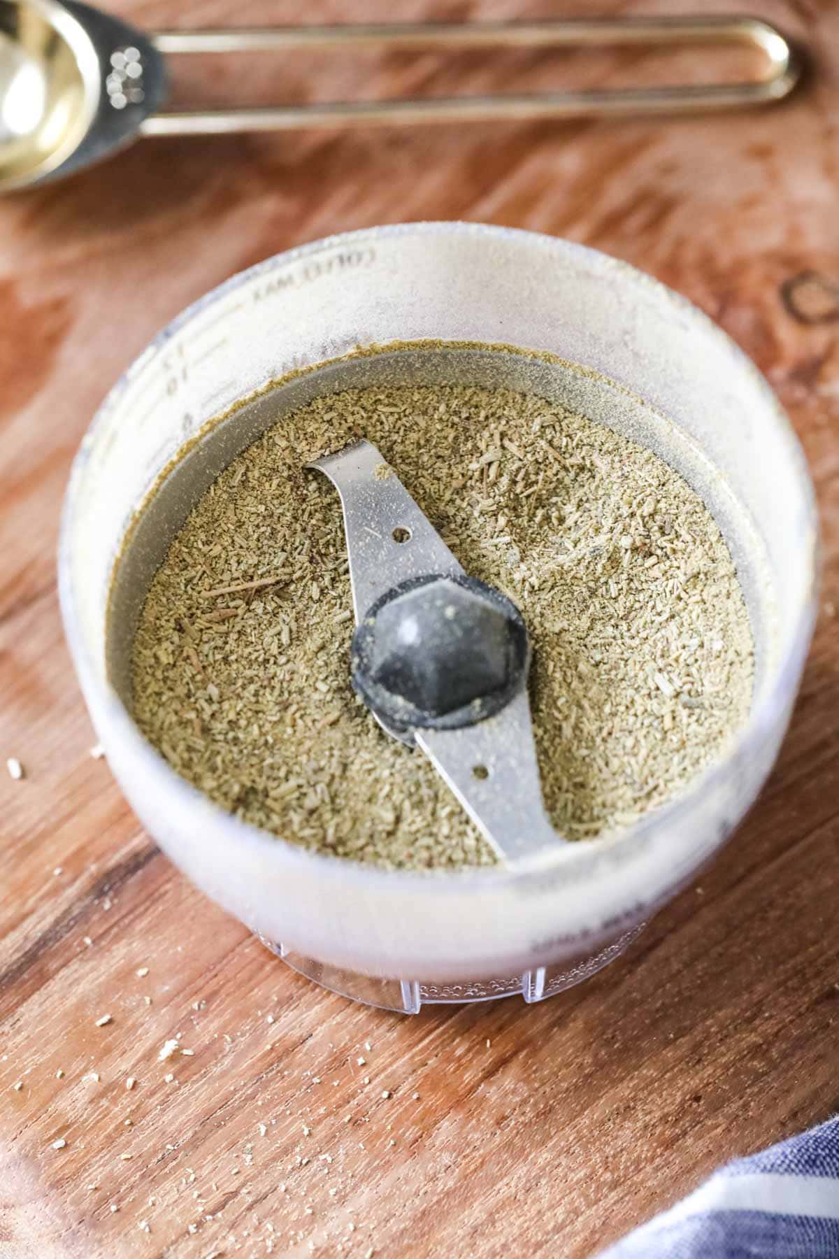 Overhead view of a mini food processor that's been used to grind herbs into powder.