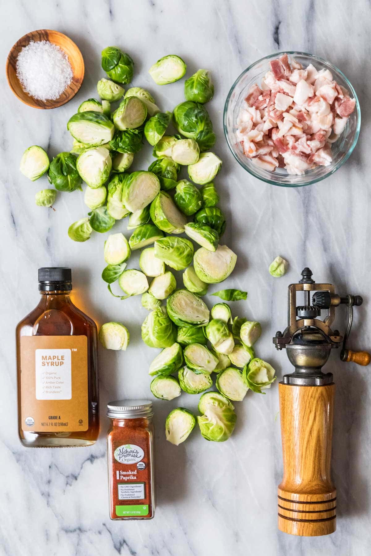 Overhead view of ingredients including brussels sprouts, bacon, maple syrup, and spices.