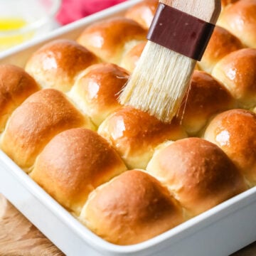 Melted butter being brushed onto make ahead dinner rolls.