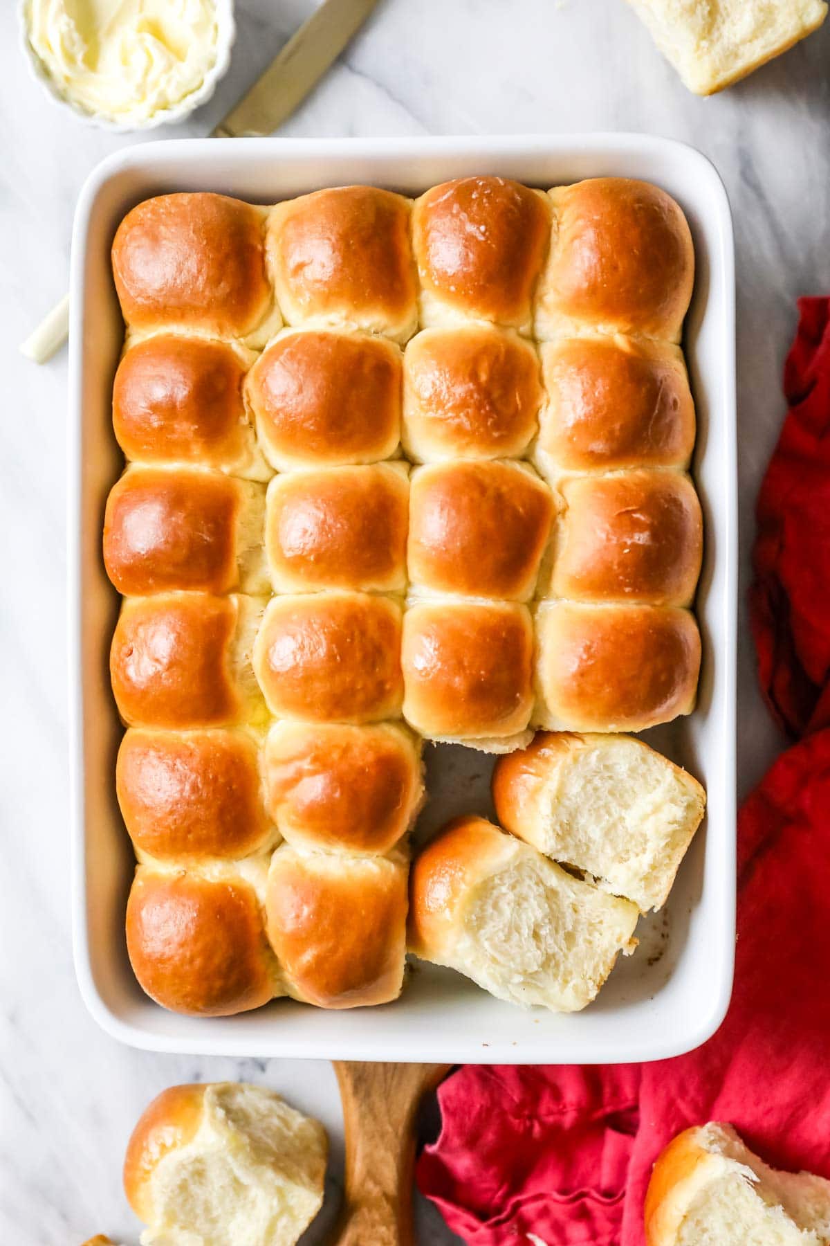 Overhead view of a pan of make ahead dinner rolls with two of the rolls turned on their sides to show their height.