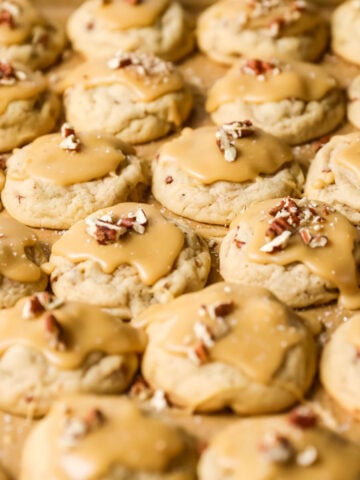 Close-up view of many rows of praline cookies topped with pecan pieces.