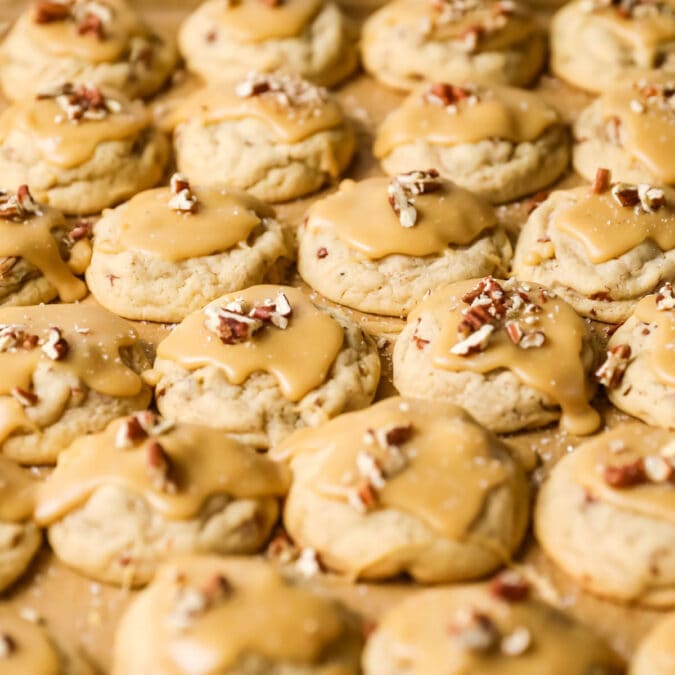 Close-up view of many rows of praline cookies topped with pecan pieces.