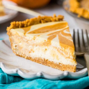 Slice of swirled pumpkin cheesecake pie on a plate.