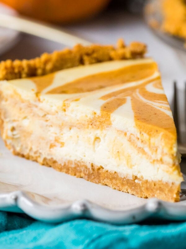 Slice of swirled pumpkin cheesecake pie on a plate.