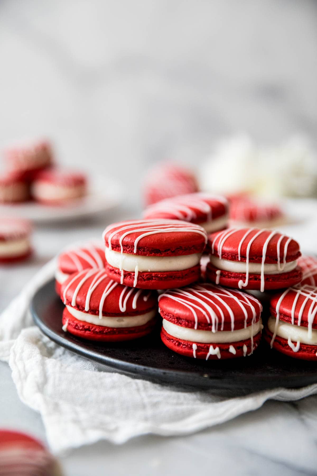 Pile of red and white macarons on a black plate.