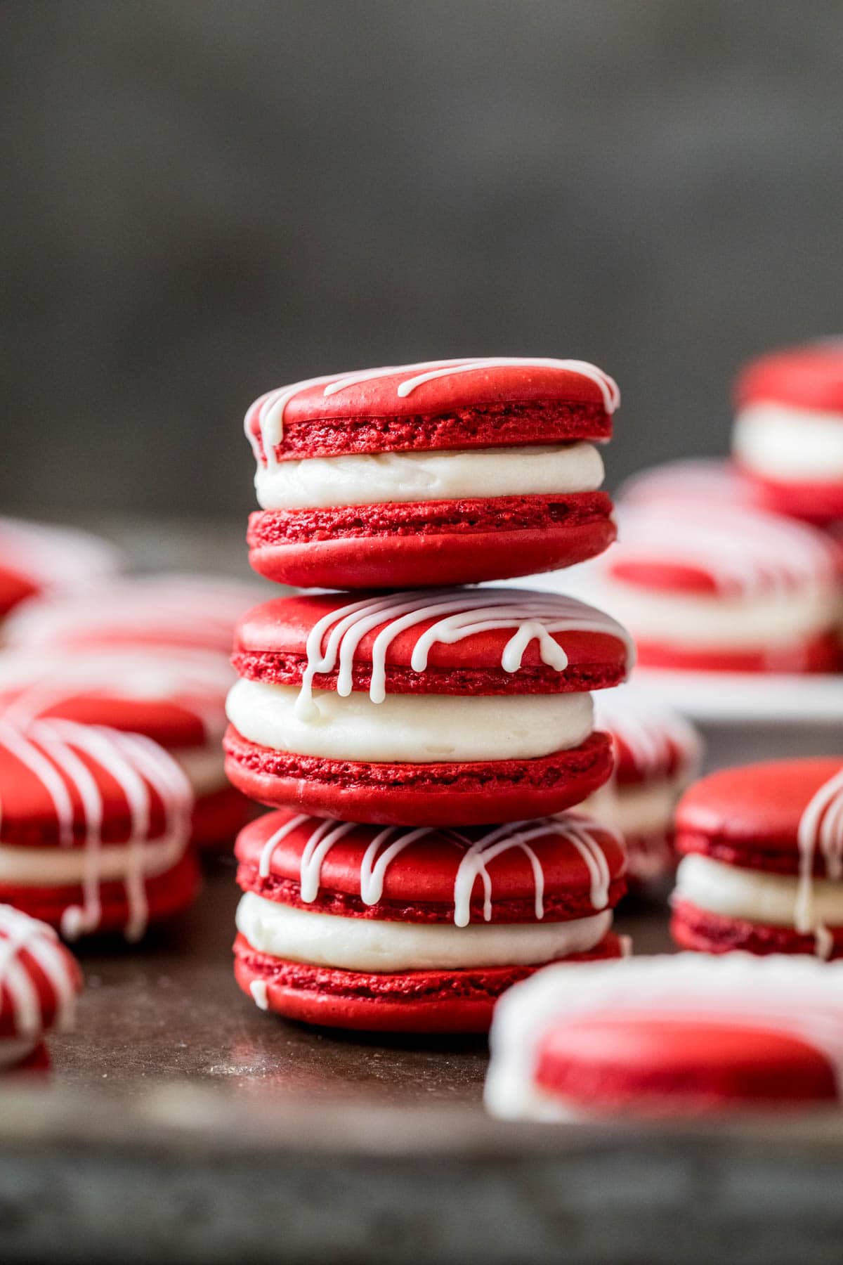 Three red velvet macarons stacked vertically on top of each other.