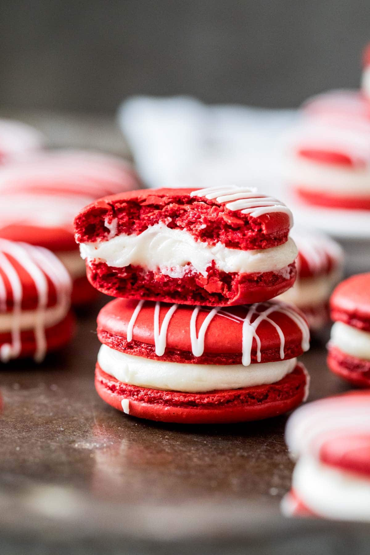 Two red macarons stacked on top of each other with the top cookie missing a bite.