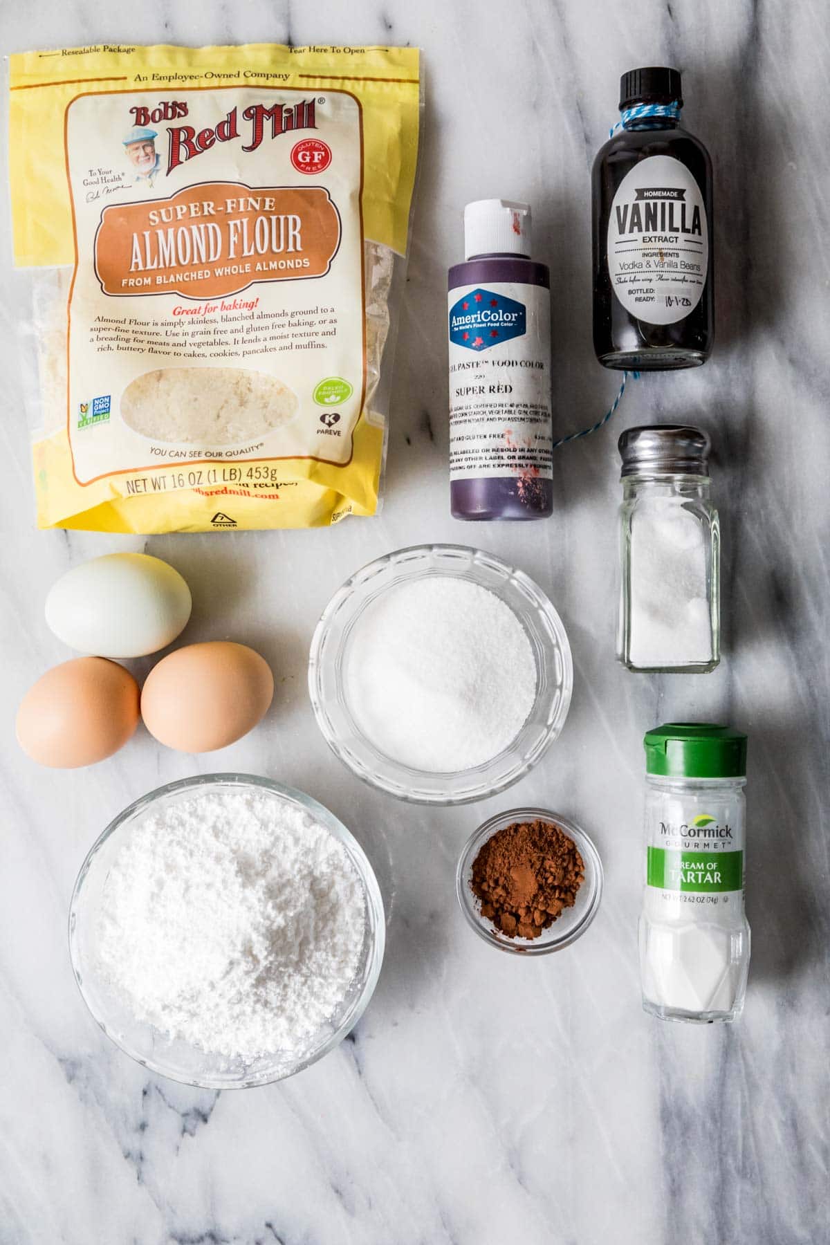 Overhead view of ingredients including almond flour, red food coloring, cream of tartar, and more.