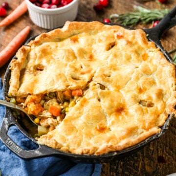 Turkey pot pie made in a cast iron pan with one slice missing.