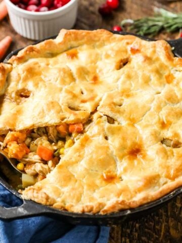 Turkey pot pie made in a cast iron pan with one slice missing.