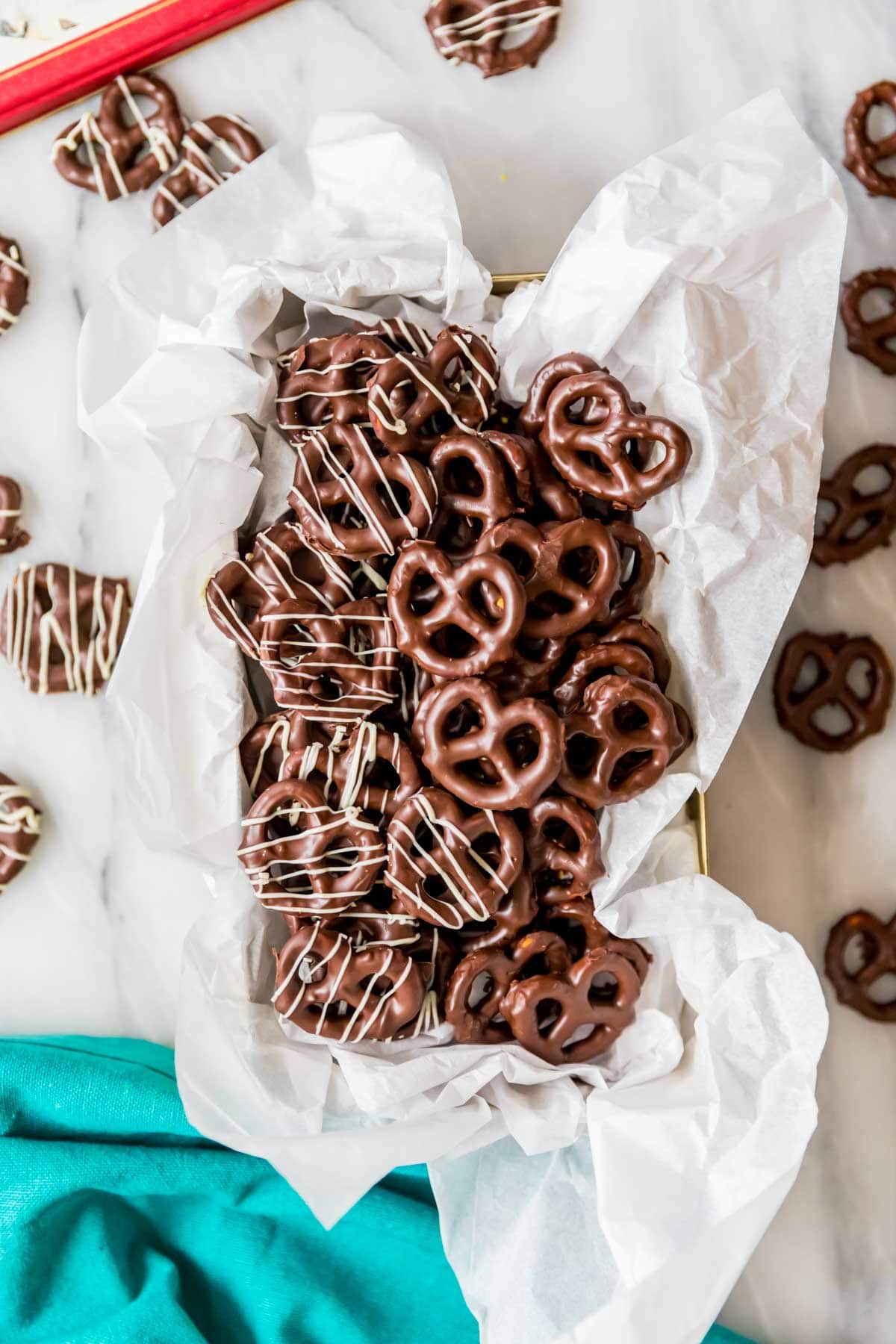 Overhead view of chocolate dipped pretzels in a parchment lined bread pan.
