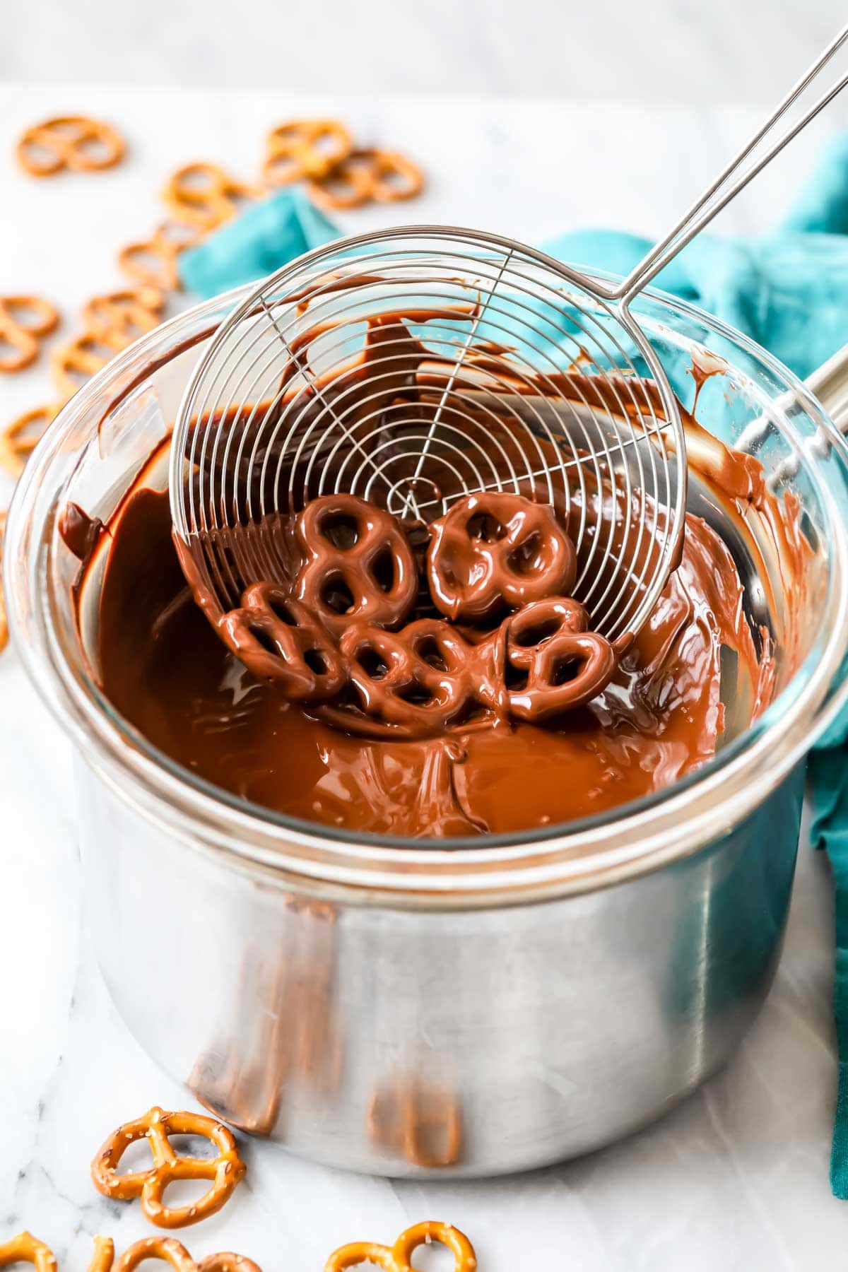 Spider dipping pretzels into chocolate melting over a double boiler.