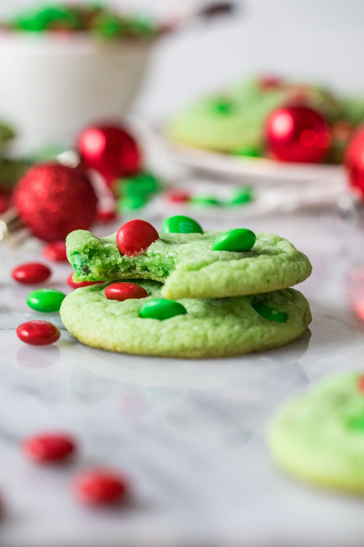 Two green cookies stacked on top of each other with the top cookie missing a bite.