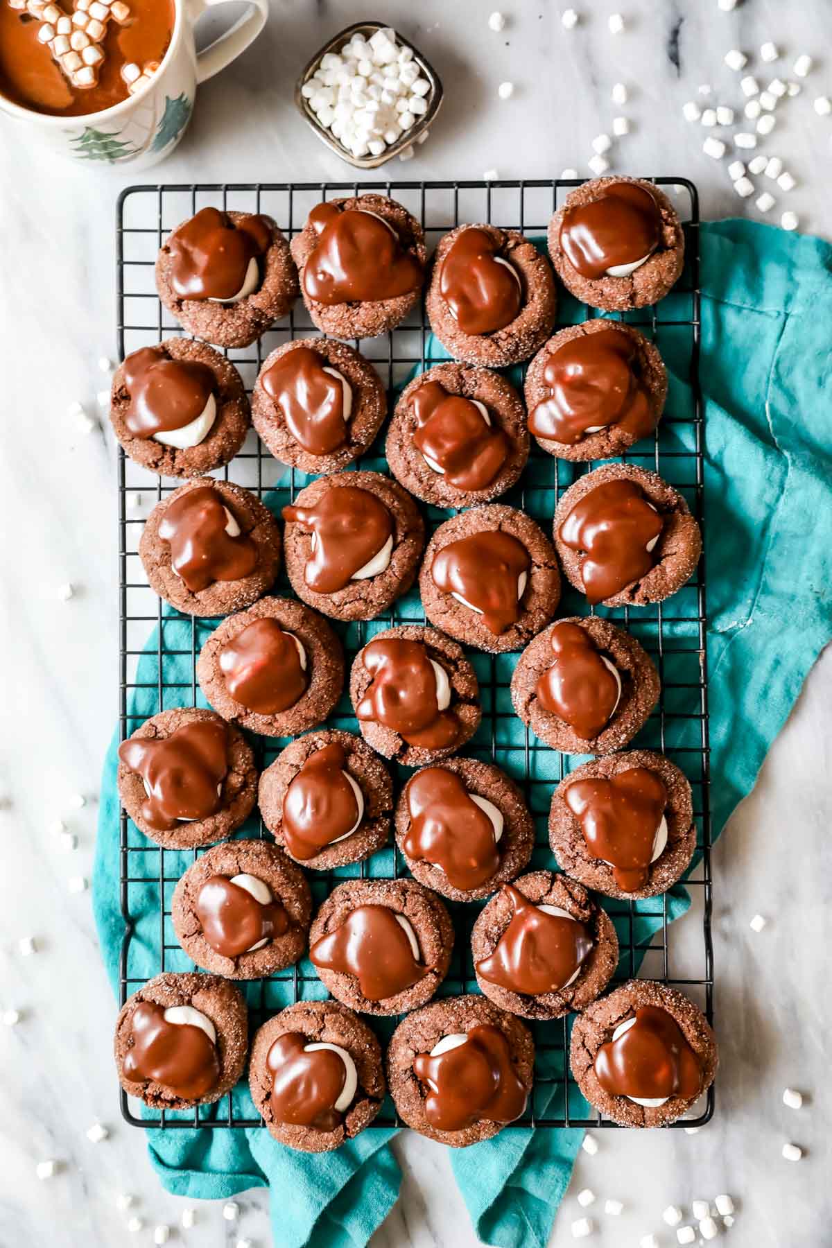 Overhead view of a cooling rack of chocolate cookies topped with marshmallows and chocolate ganache.