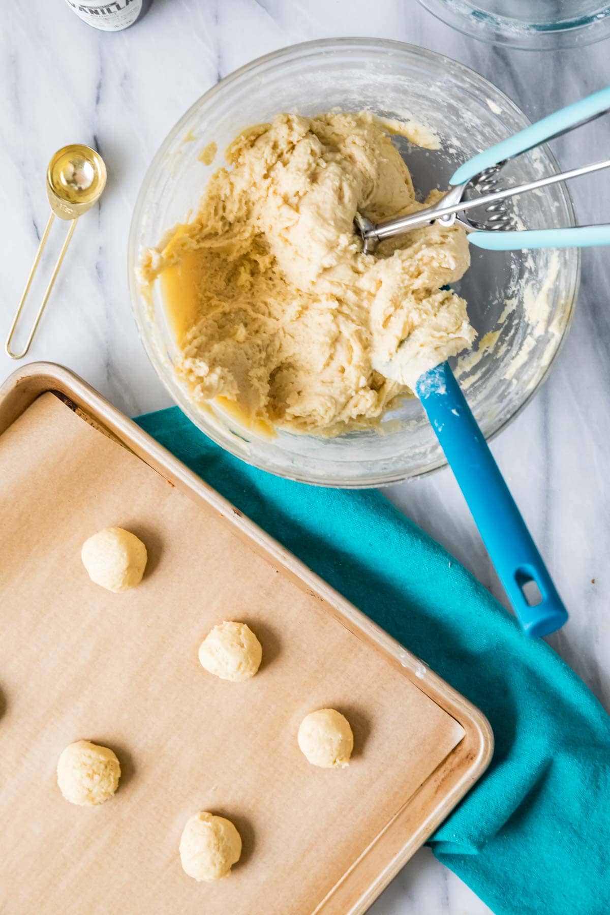 Overhead view of cookie dough being scooped onto a parchment lined cookie sheet.