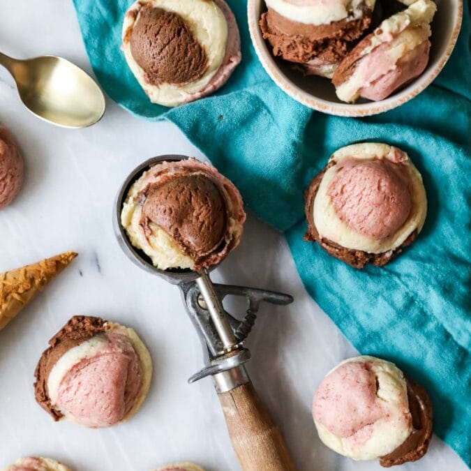 Neapolitan cookies scattered across a countertop with one cookie resting in an ice cream scoop.