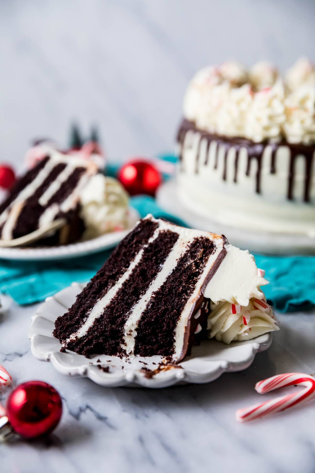 Slice of peppermint bark cake on a white plate with one bite missing.