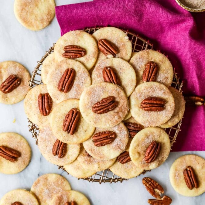 Overhead view of sand tarts made with pecans arranged on a cooling rack.