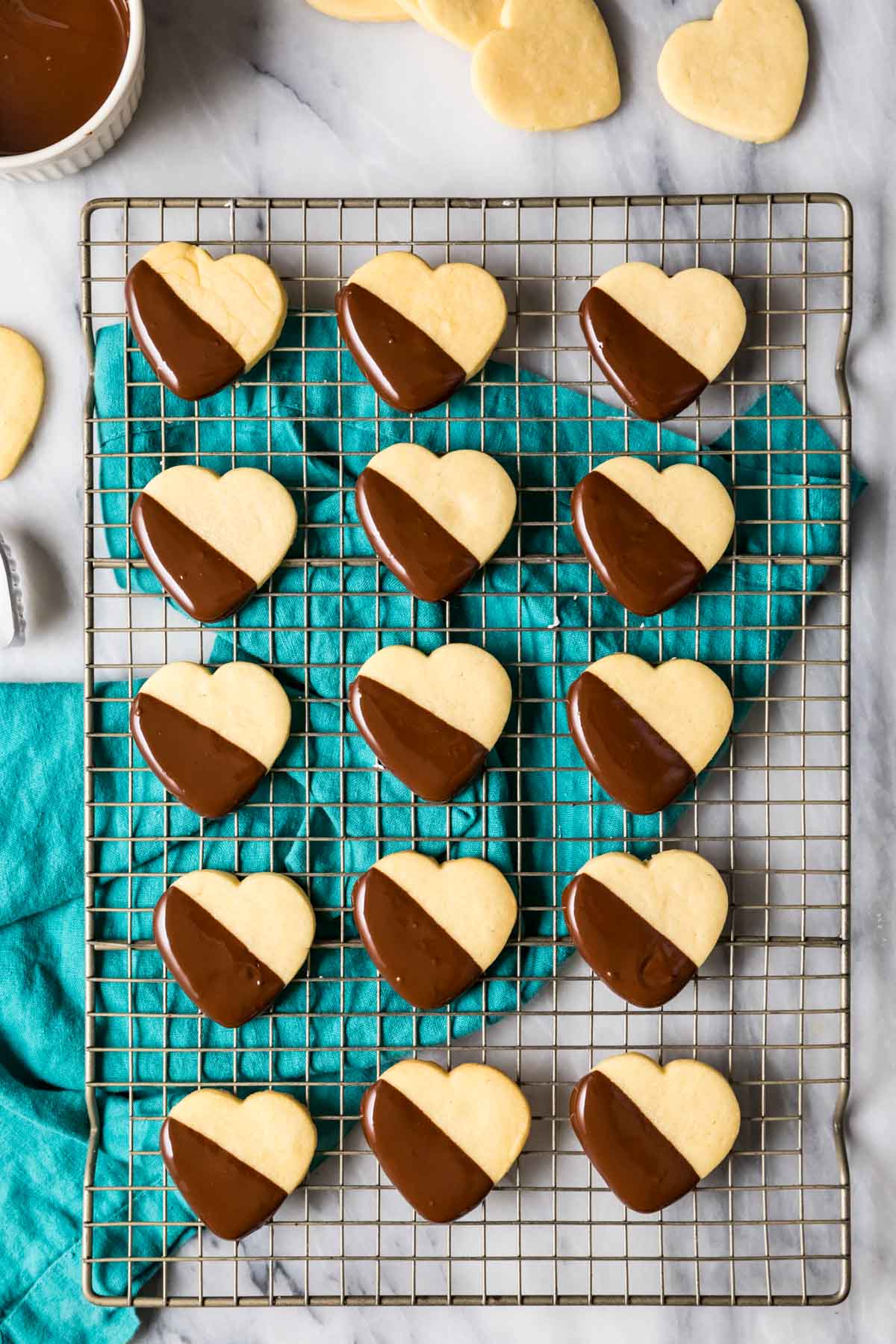 Overhead view of heart shaped shortbread cookies half dipped in chocolate on a cooling rack.