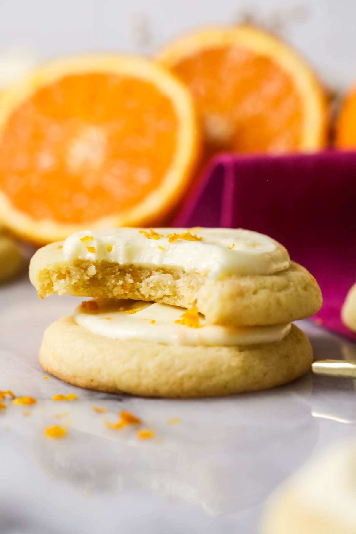 Two orange cookies stacked on top of each other with the top cookie missing one bite.
