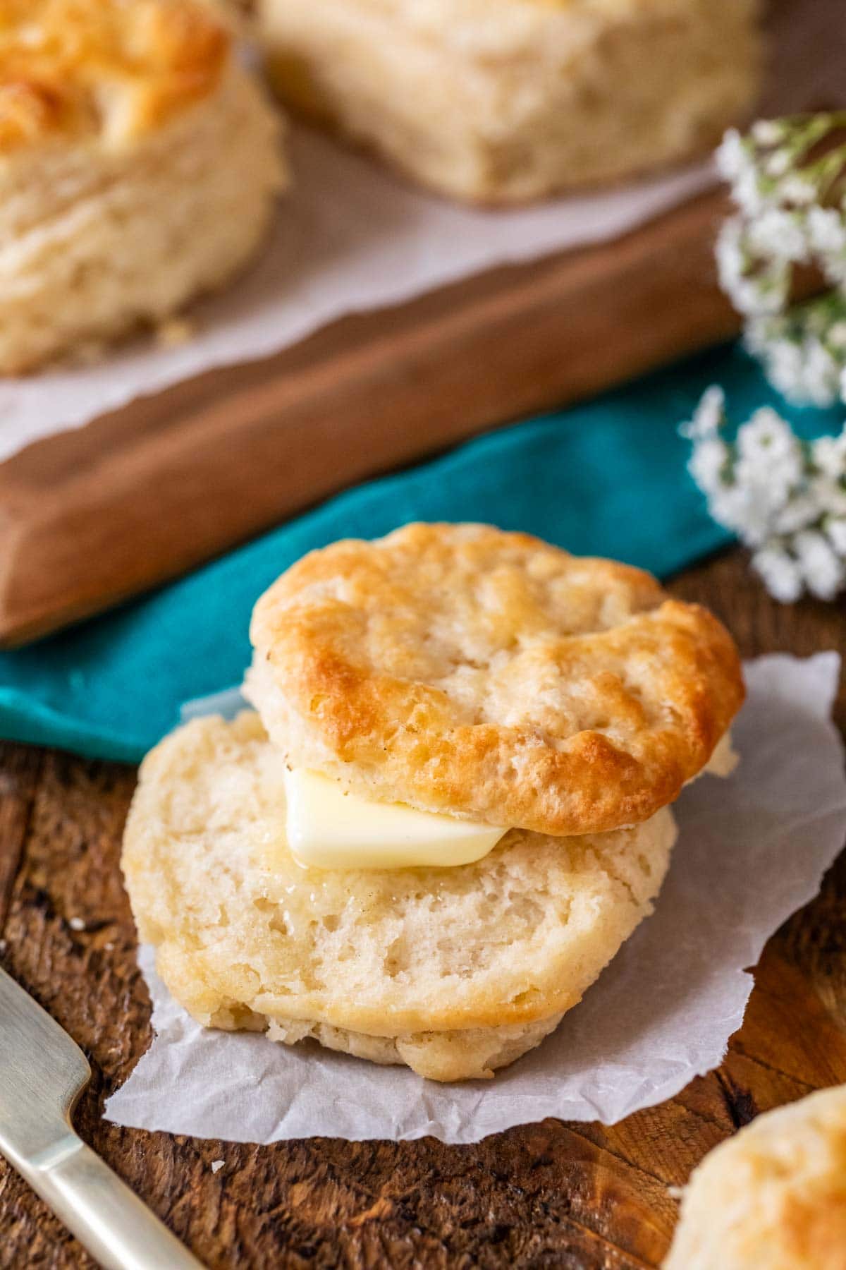 Golden brown biscuit that's been cut in half and topped with butter.