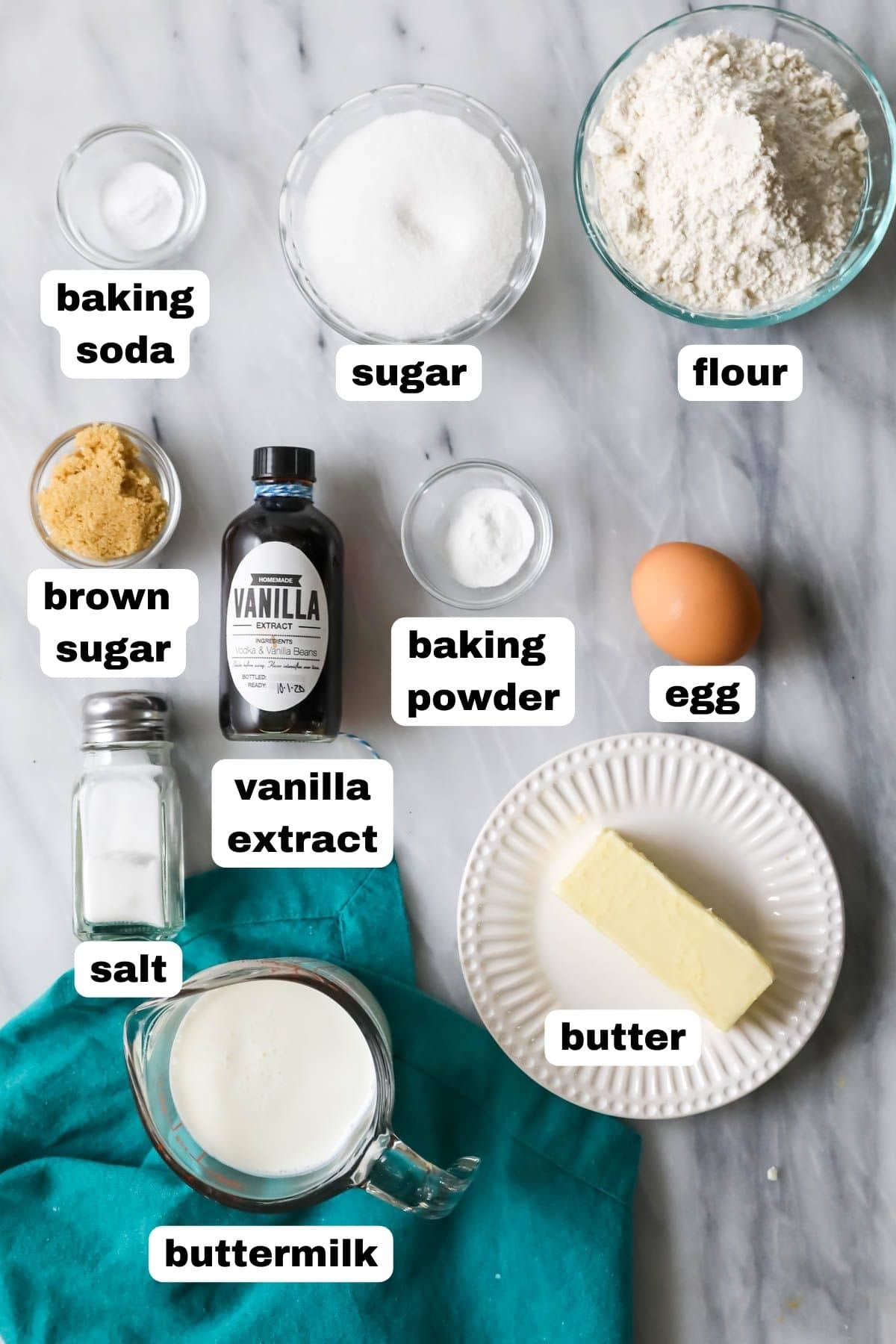 Overhead view of labelled ingredients including flour, vanilla, butter, brown sugar, and more.